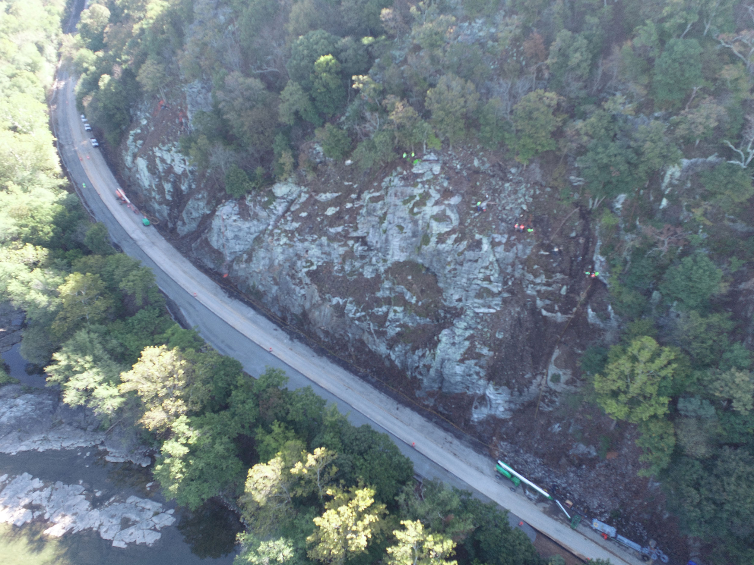 First step in mitigating a rockfall area includes removing loose or possibly unstable existing rock from the surface.  Here we can see crews suspended on the slope, using prybars and hand tools to bring down those rocks.
